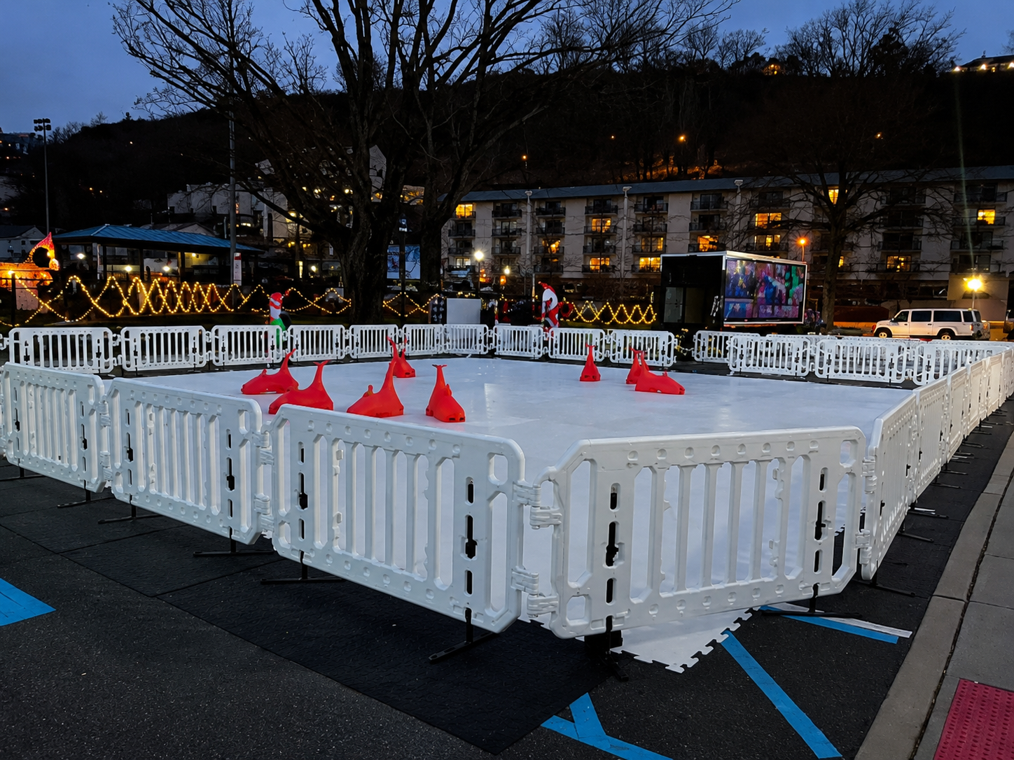 Portable ice rink setup with white safety barriers and skate aids before an outdoor event